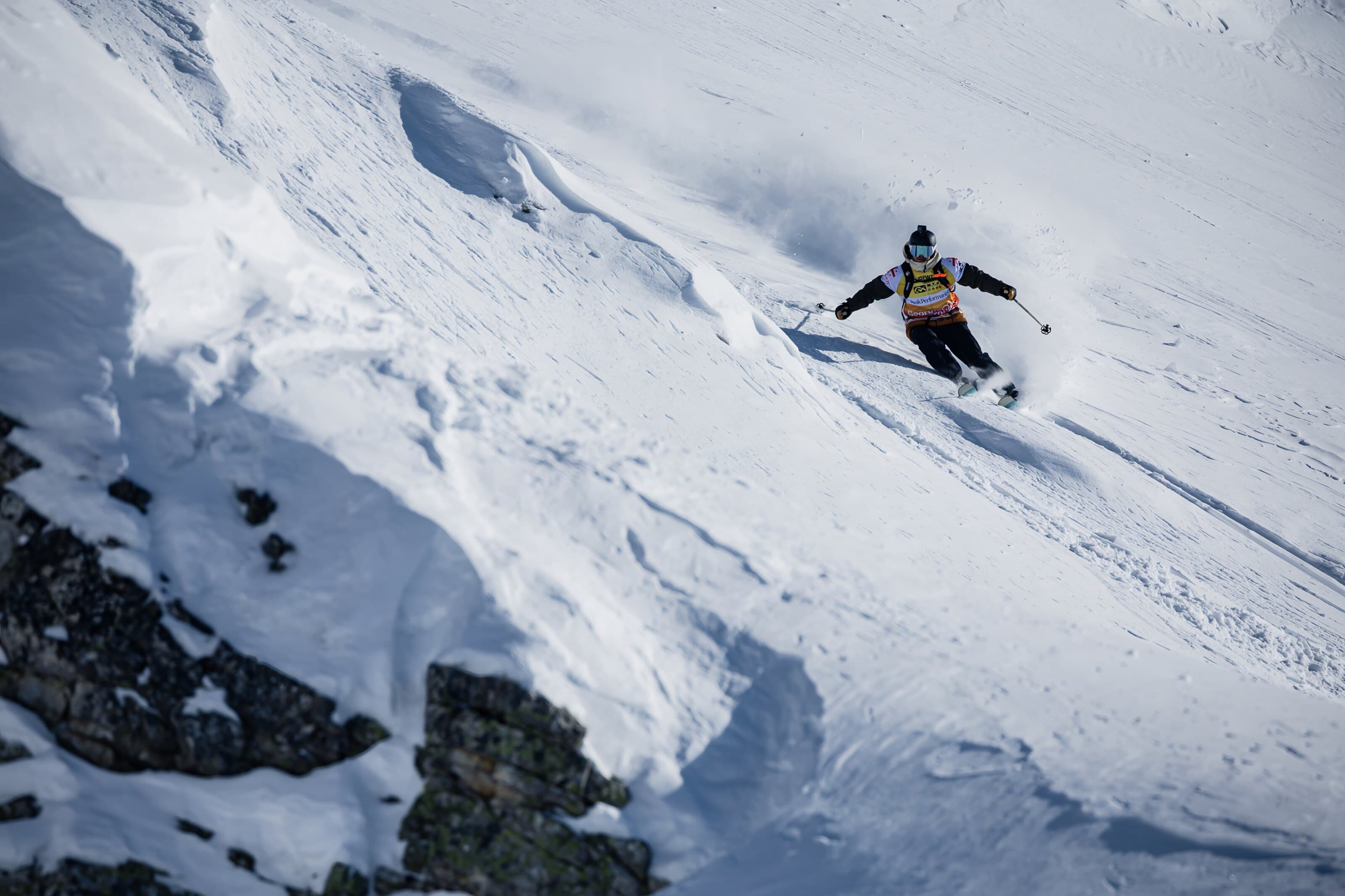 A skier mid-run on a steep competition face